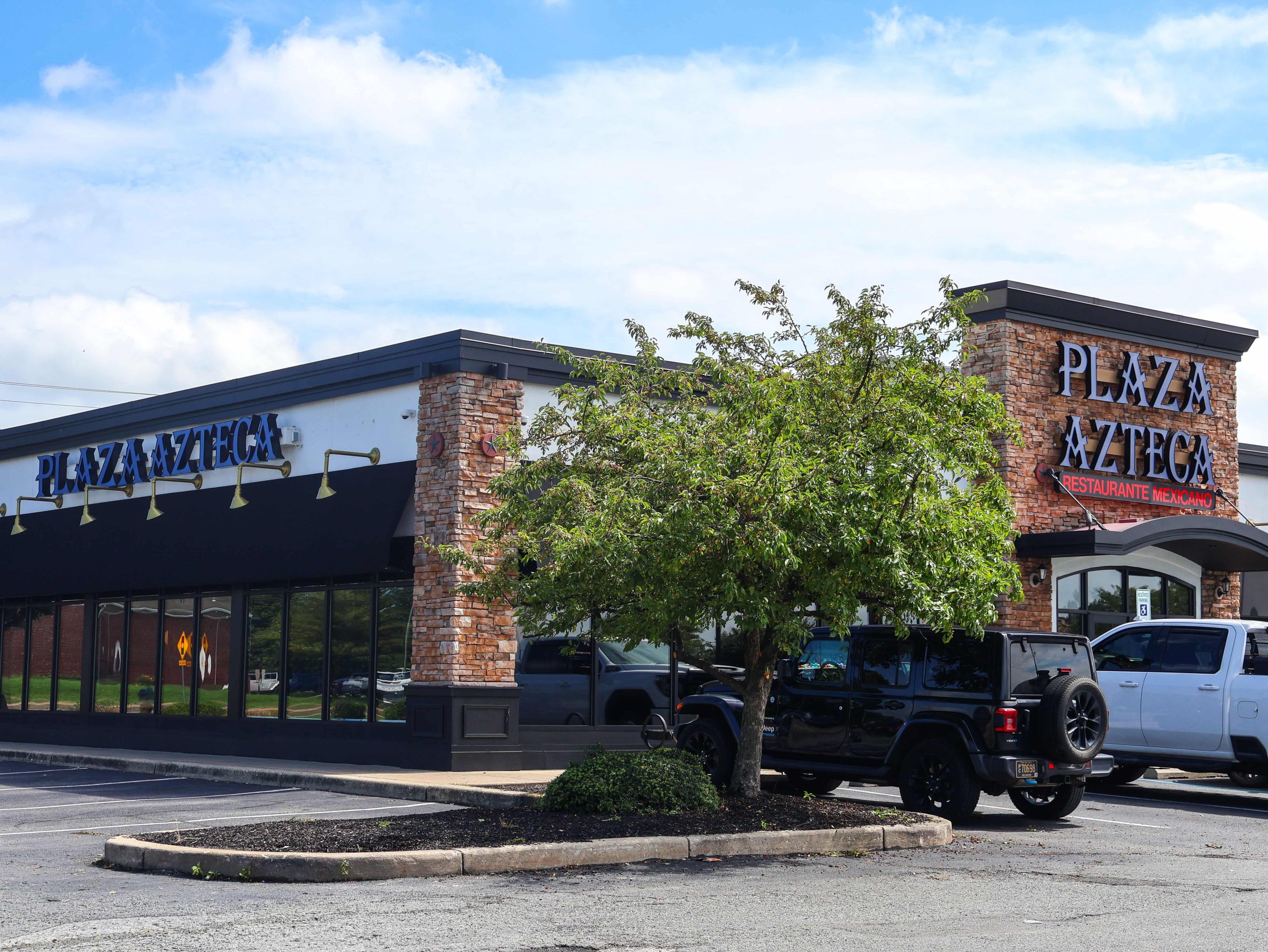 Plaza Azteca Mexican restaurant storefront with brick pillars, tree, and parked vehicles at Glendale Plaza Shopping Center