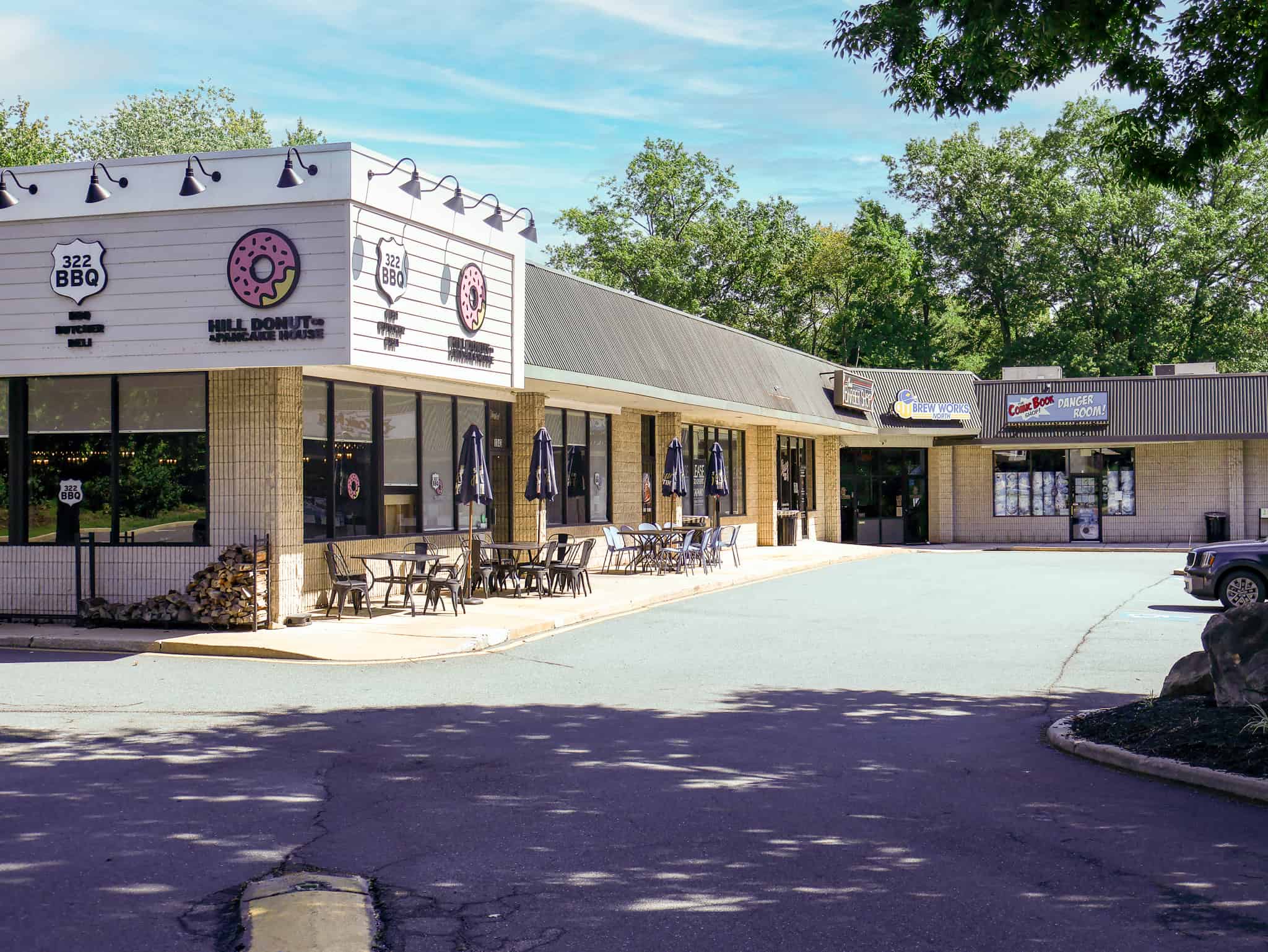 Strip mall storefront at Plaza III with 322 BBQ, Hill Donut Co, Brew Works North and Comic Book Shop signage
