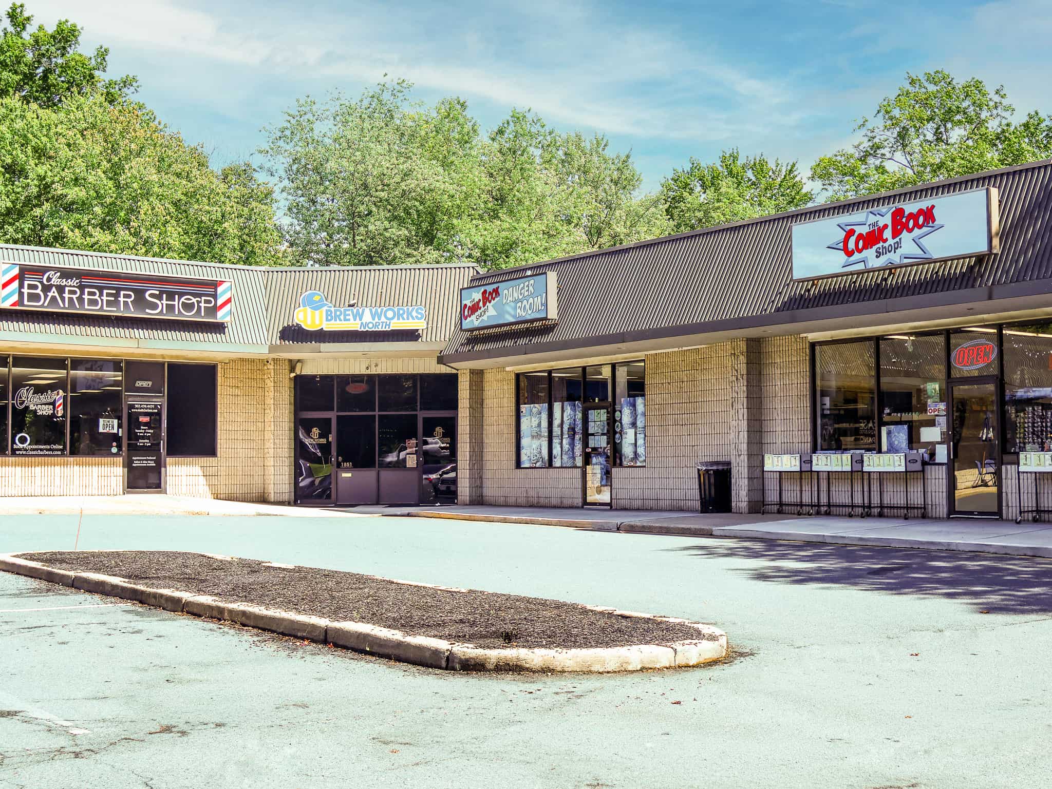 Strip mall storefronts including Classic Barber Shop, Brew Works North, and The Comic Book Shop with parking lot