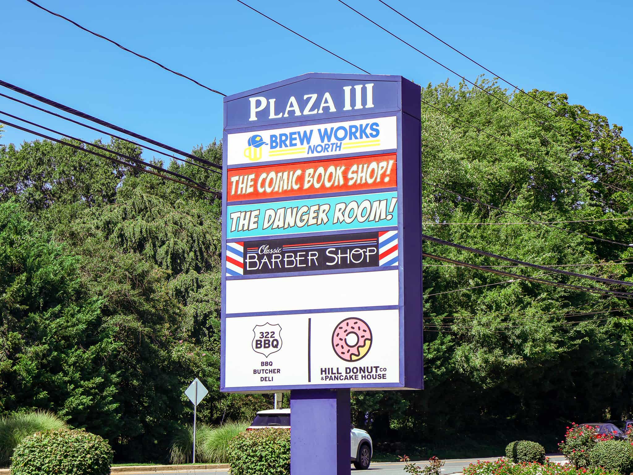 Plaza III shopping center pylon sign listing Brew Works North, Comic Book Shop, Barber Shop, BBQ and Donut businesses