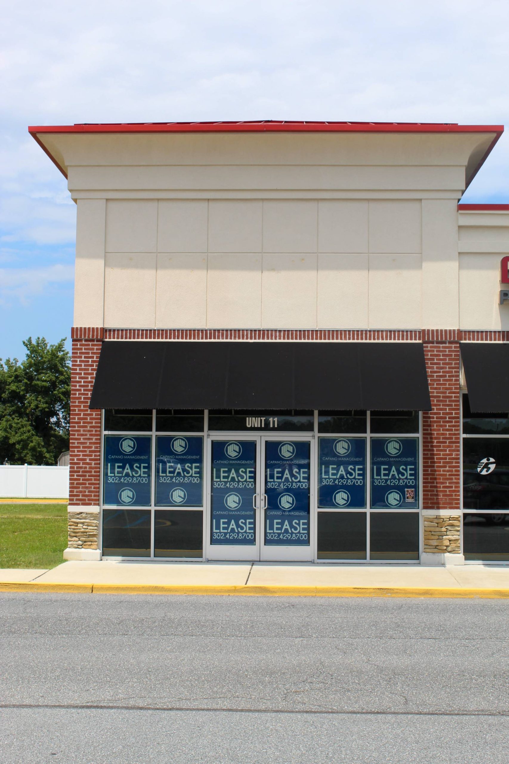Vacant retail storefront at Unit 11 displays Capano Management lease signage with contact number in the windows.