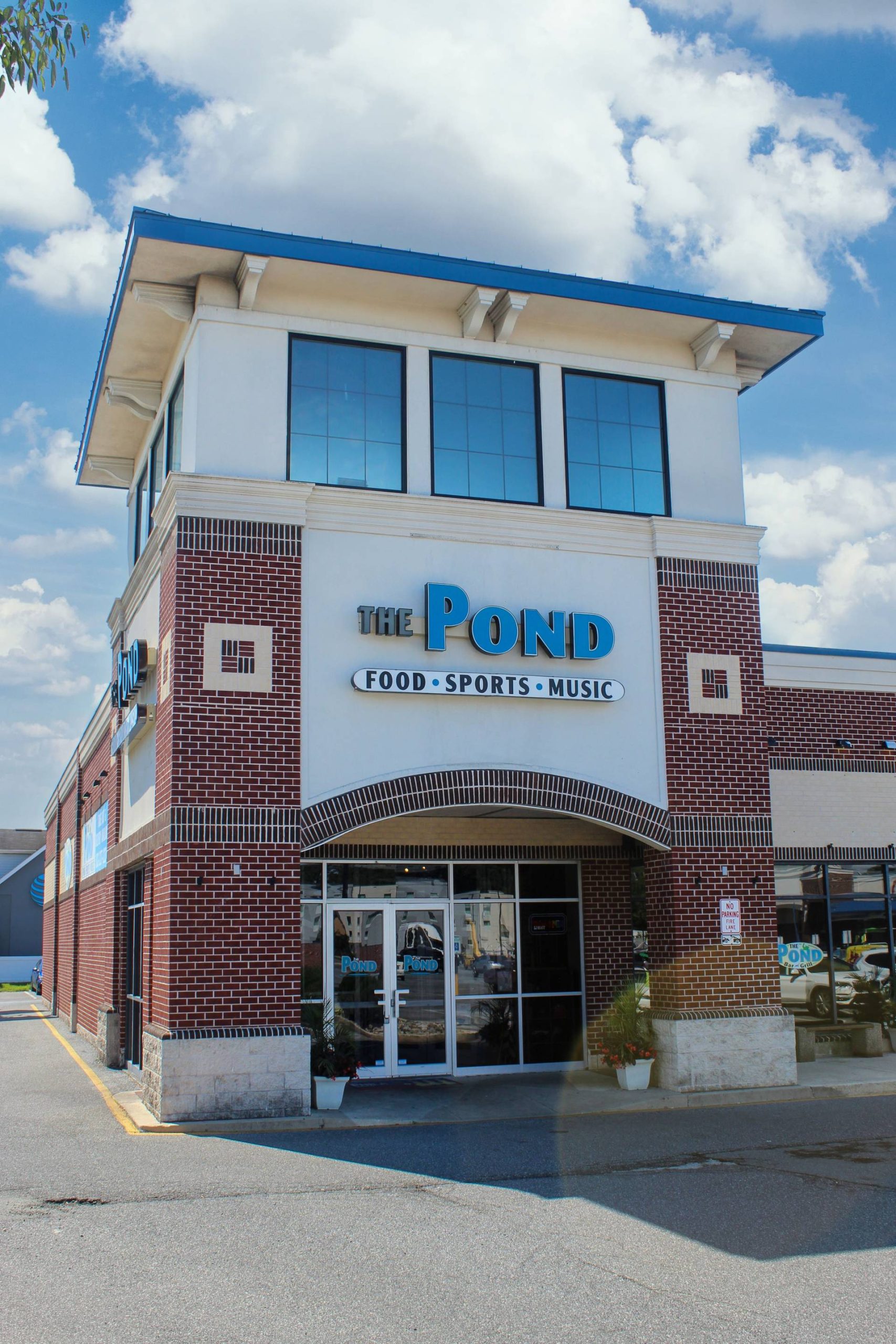 Brick and glass storefront of The Pond restaurant featuring food, sports, and music signage at Shops at Seacoast.