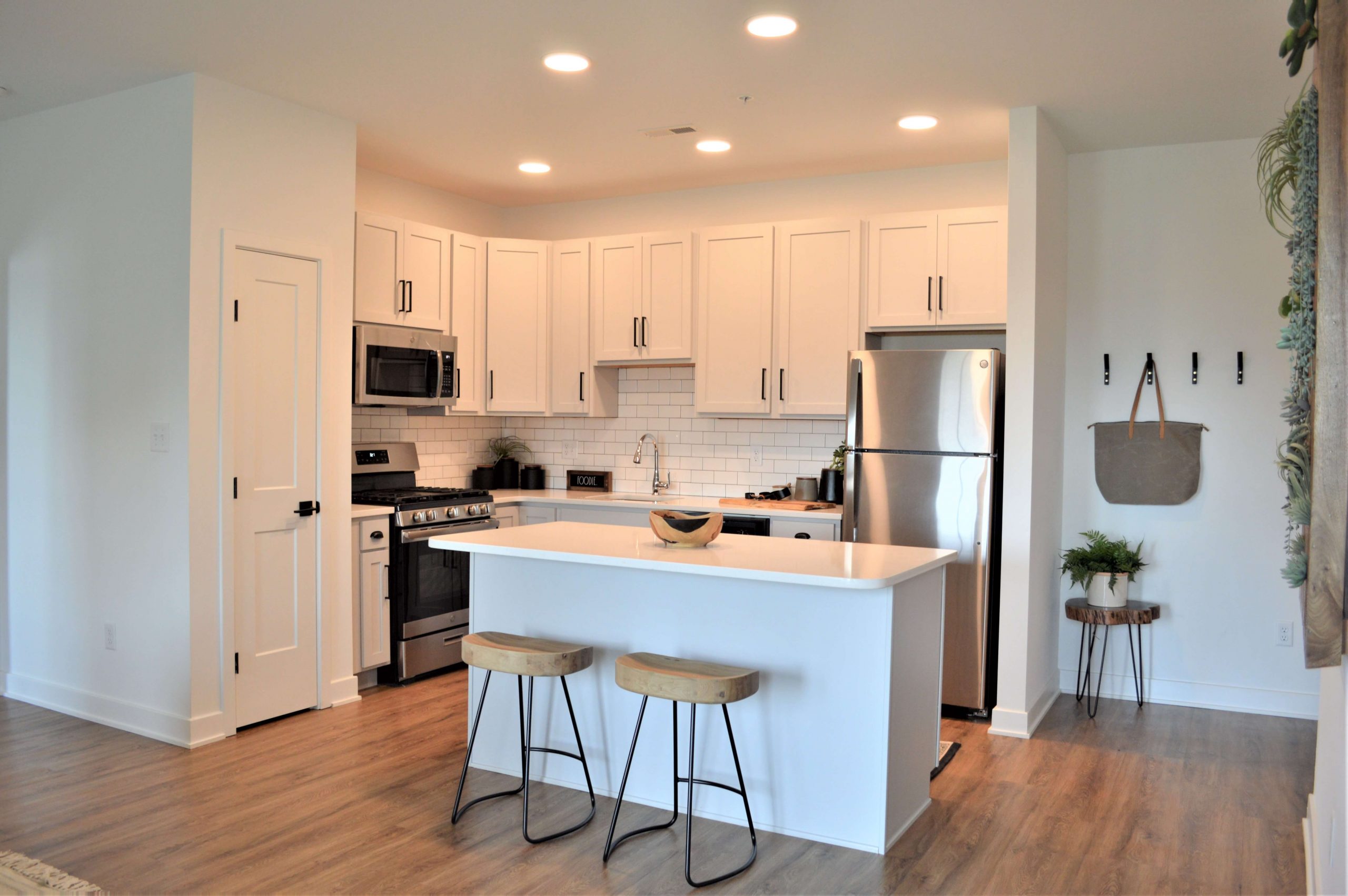 Open kitchen with white cabinetry, stainless steel appliances, subway tile backsplash, and a center island with seating.