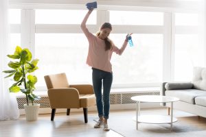 An adult woman celebrating with cleaning supplies
