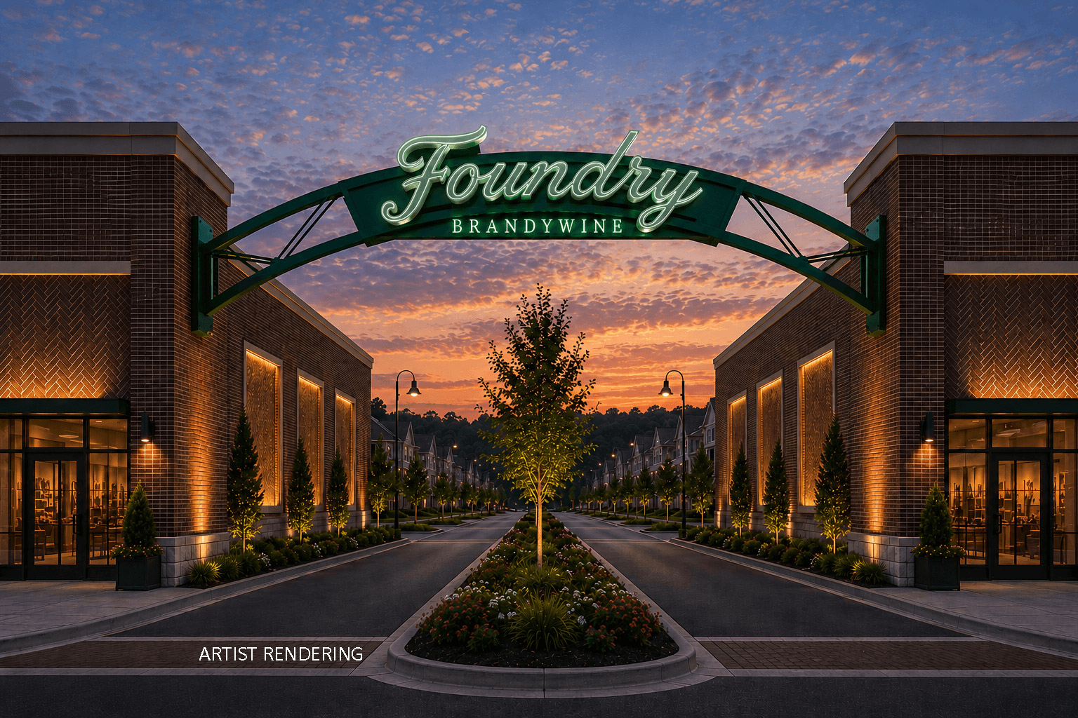Illuminated Foundry Brandywine archway sign spans a tree-lined entrance between brick retail buildings at dusk
