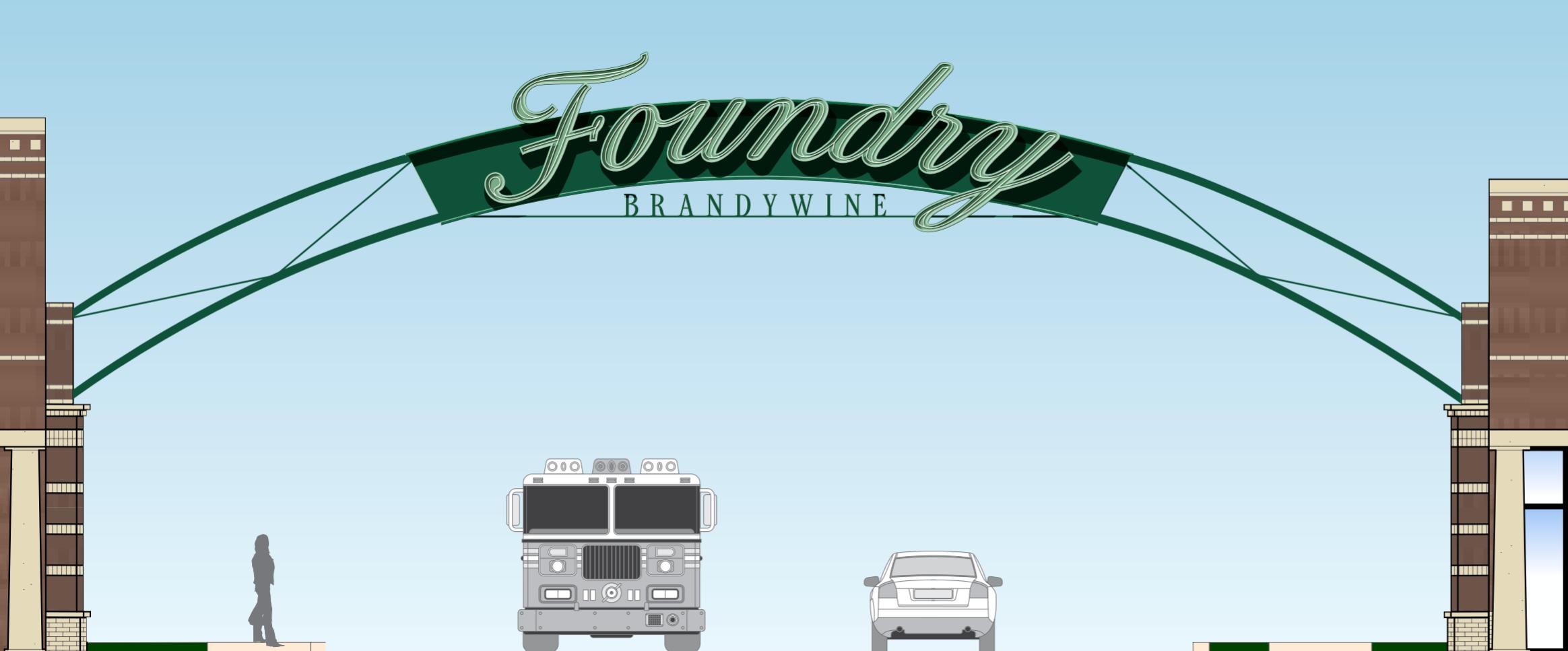 Green archway sign reading Foundry Brandywine spans the entrance road between two brick pillars in Wilmington, DE.