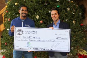 The CEO of Capano Management and CEO of The WRK Group holding a giant novelty check for $300,000