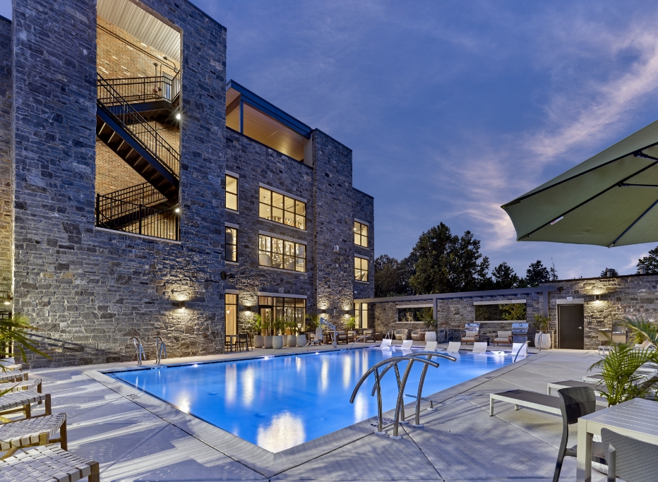 Twilight view of The Phoenix stone building with outdoor pool, lounge seating, and exterior staircase