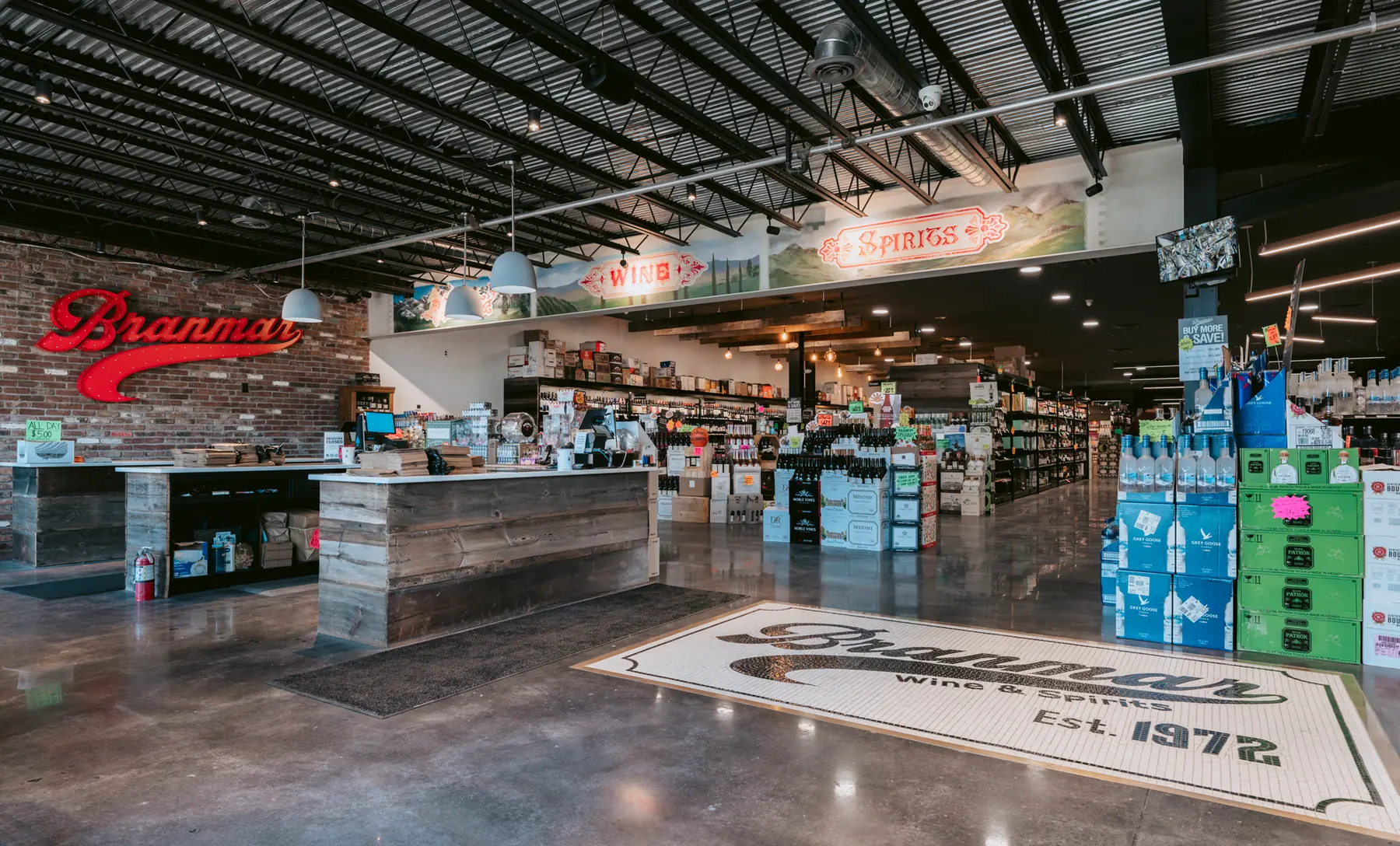 Interior of Branmar Wine & Spirits store featuring checkout counters, wine and spirits displays, and a mosaic floor logo reading Est. 1972.