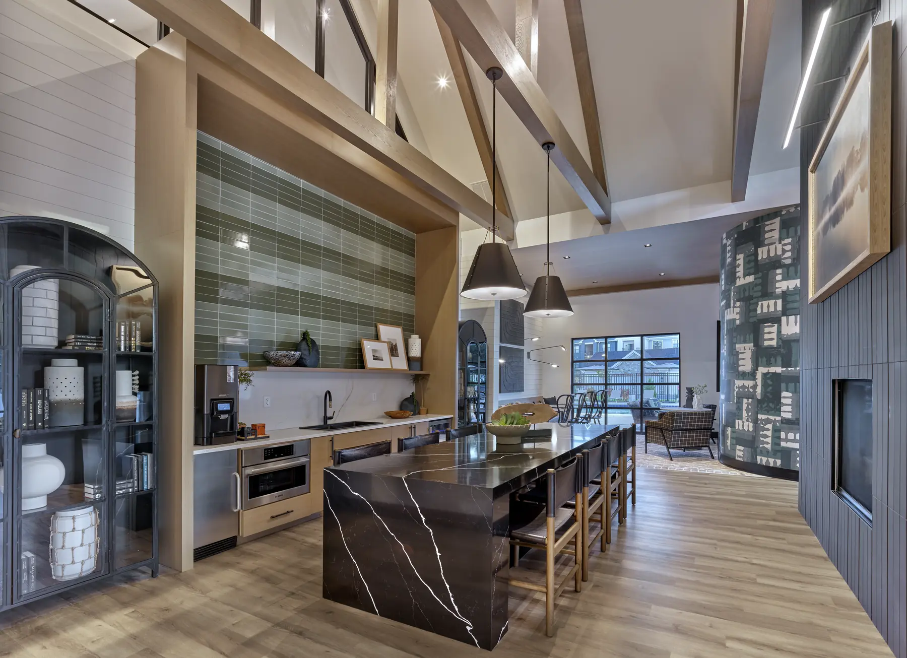 Open-concept kitchen with marble island, pendant lighting, exposed beams, and view into a lounge area