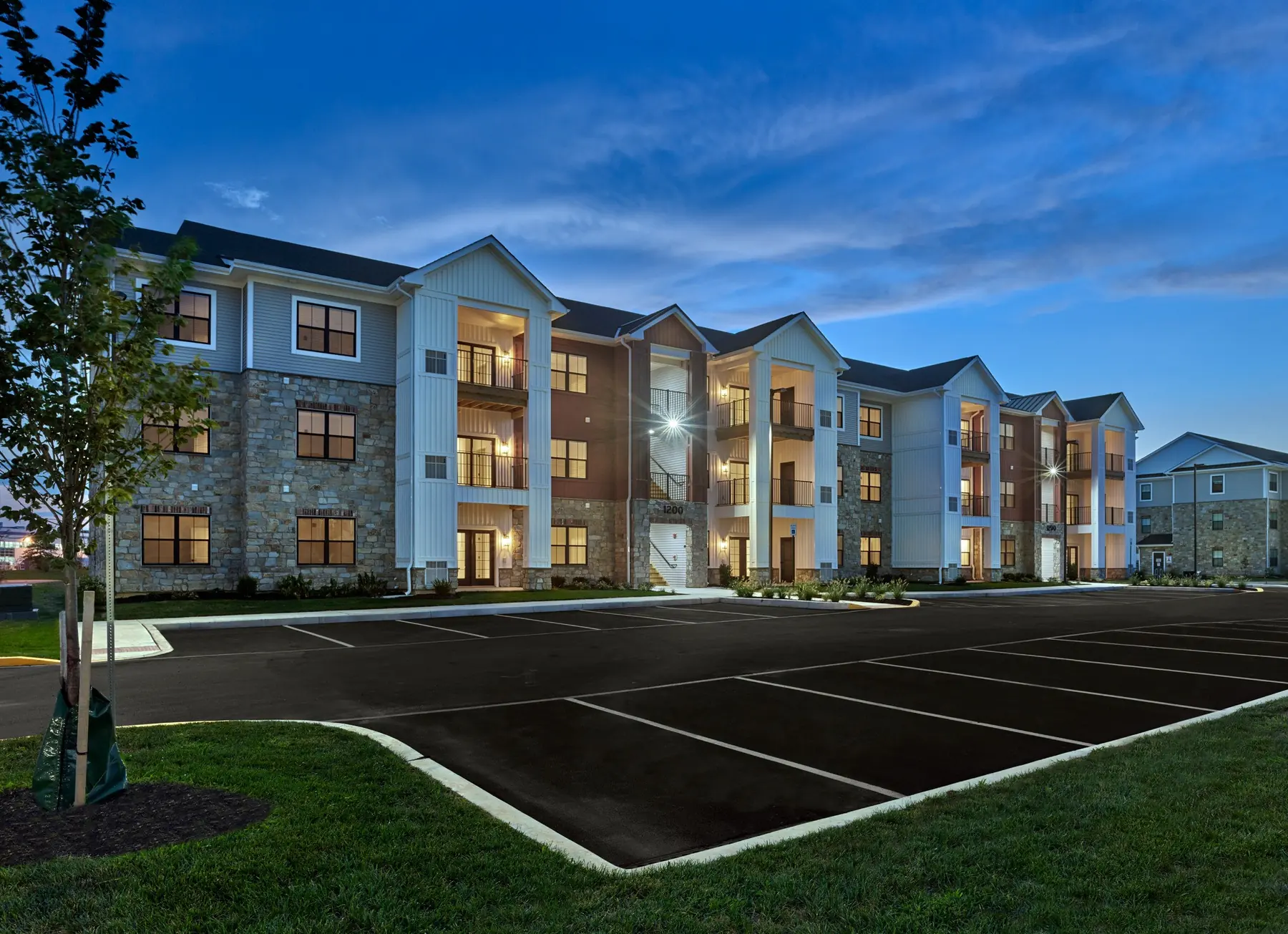 Three-story apartment building at The Reserve on Forge illuminated at dusk with stone and siding exterior and private balconies