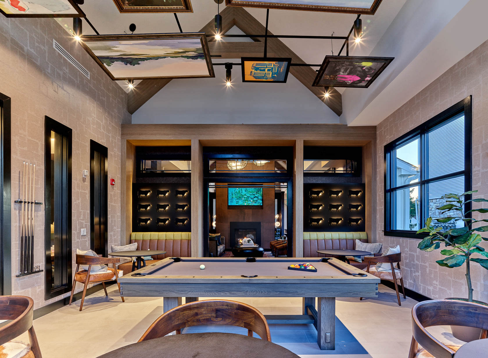 Game room lounge at The Reserve on Forge with a pool table, cue racks, seating booths, and a view to a fireplace lounge.