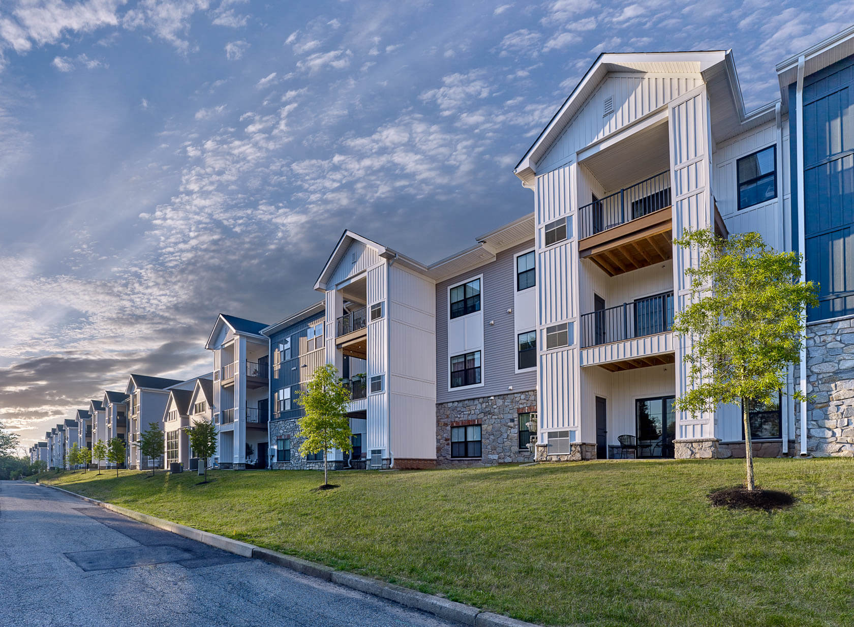 Row of multi-story apartment buildings with balconies at The Reserve on Forge under a partly cloudy sky