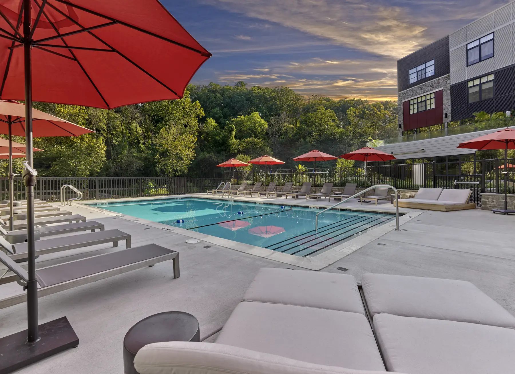 Outdoor pool with lounge chairs and red umbrellas at The Falls apartment community in Wilmington, DE