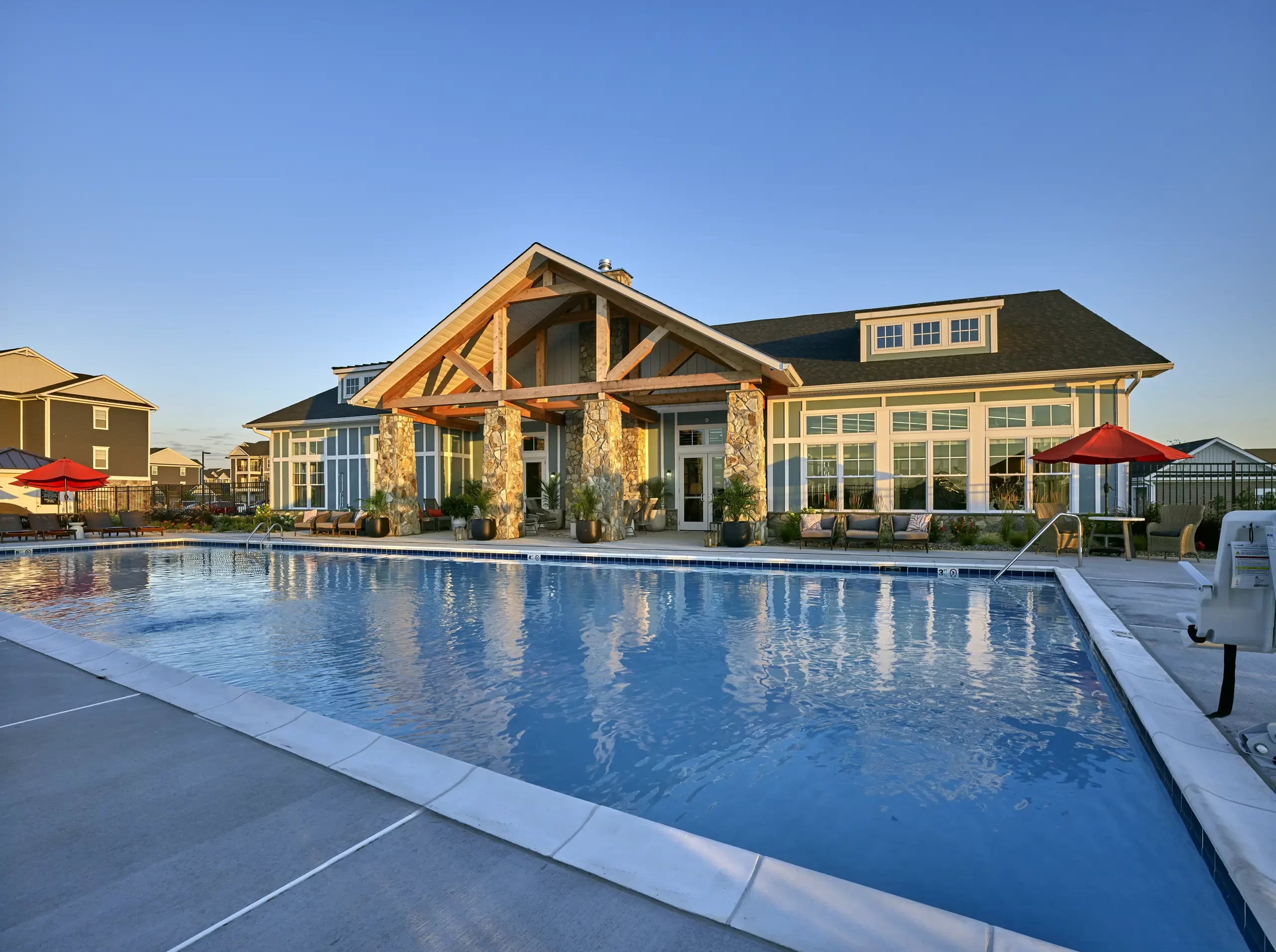 Community clubhouse pool with wood-beamed pavilion, stone columns, and lounge seating at The Falls